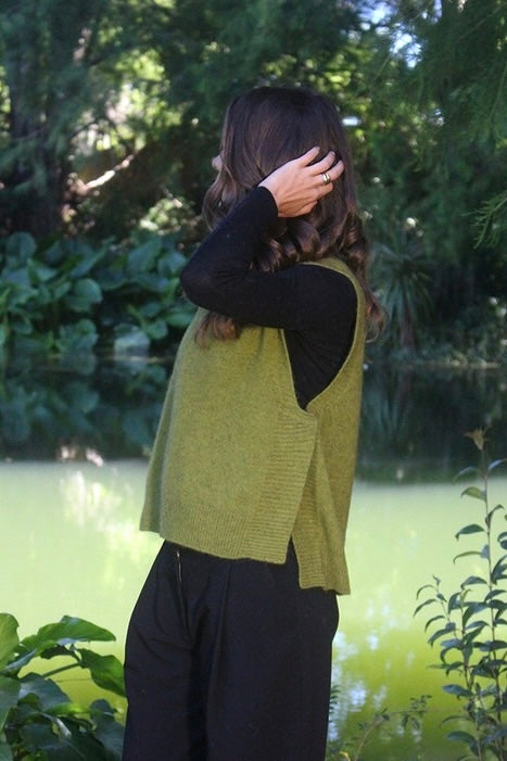 Woman standing in garden wearing green Lothlorian warm winter possum and merino wool v-neck vest