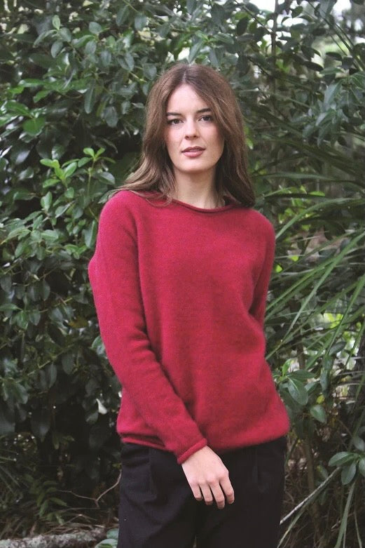 Red women's possum and merino wool crew neck jumper on female model standing in park. Lothlorian warm, soft, lightweight possum and merino wool womens pullover sweater