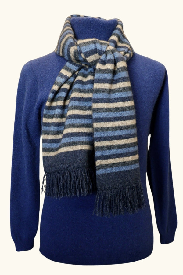 Blue striped possum and merino wool scarf with fringing wrapped around mannequins neck wearing a blue wool jumper. Warm, soft, light Lothlorian possum and merino wool scarf.