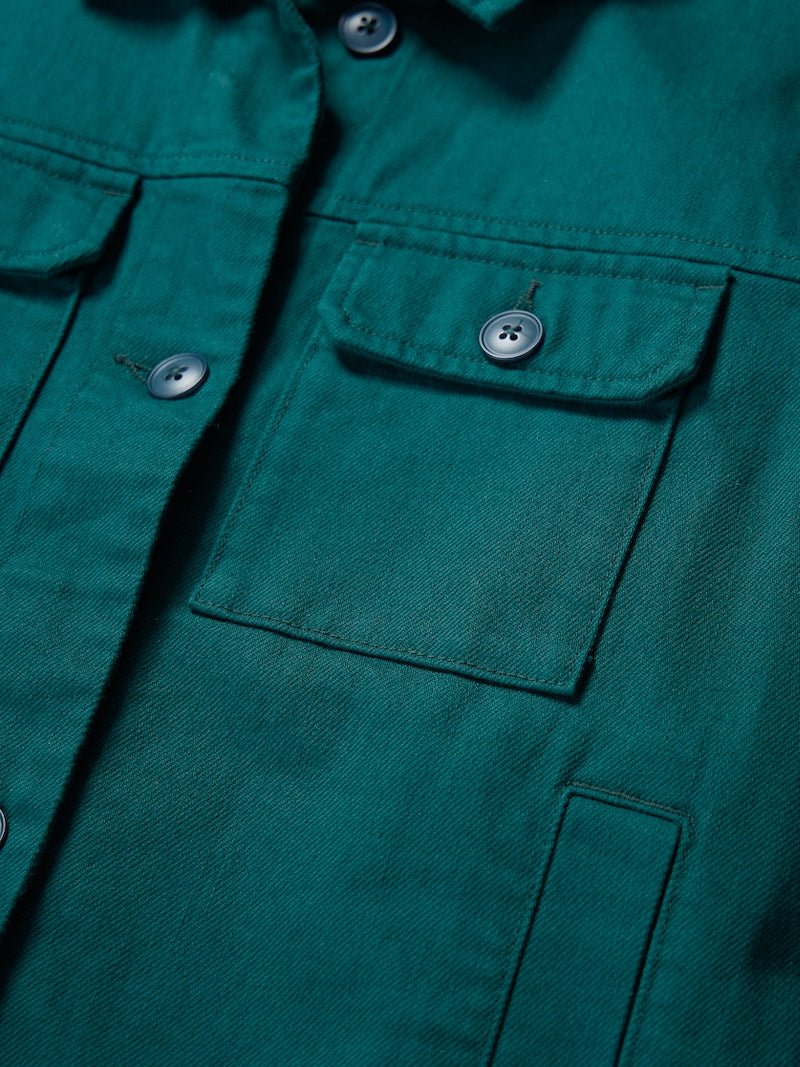 Close-up of a teal denim jacket with button details on pockets