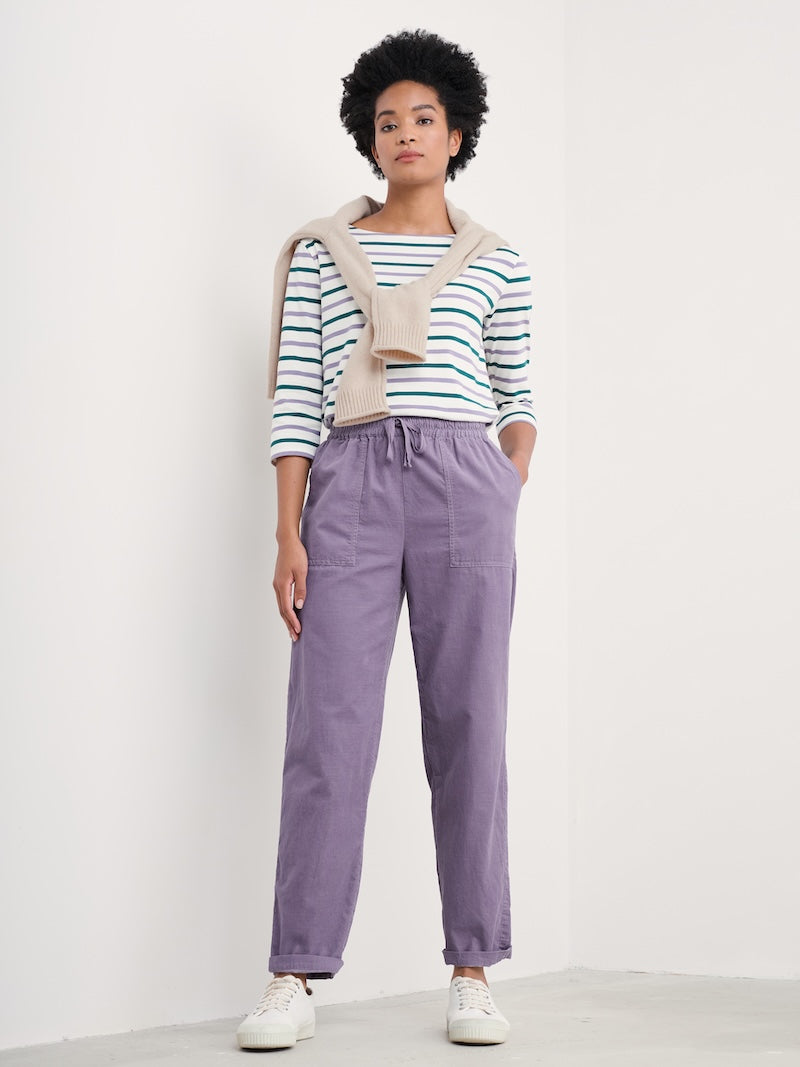 Person wearing a striped shirt and purple pants against a white background
