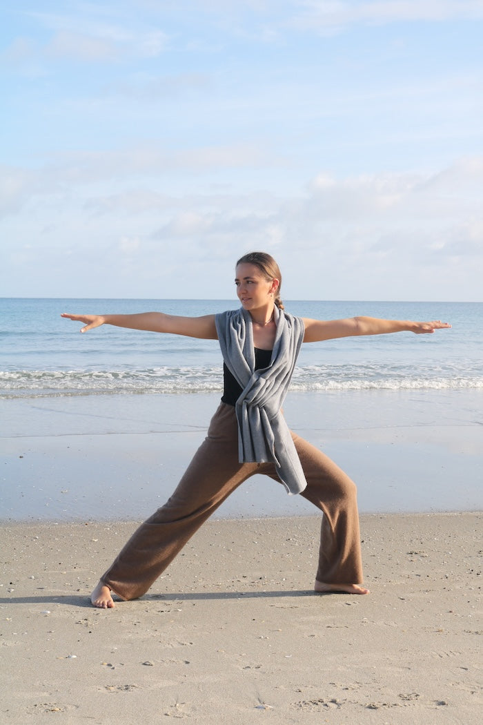Woman standing on beach wearing possum, merino wool and silk brown loungewear pant and grey poncho