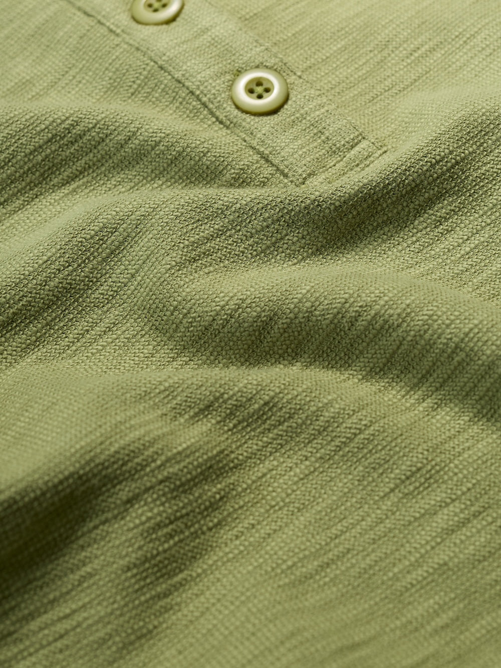 Close-up of a green textured shirt with buttons