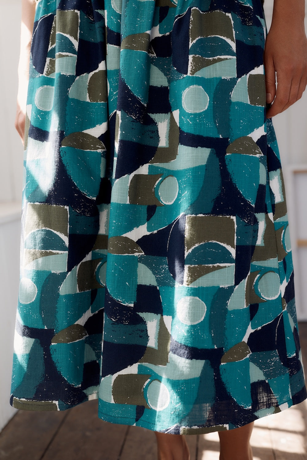 Person wearing a dress with a geometric pattern in blue, green, and gray.