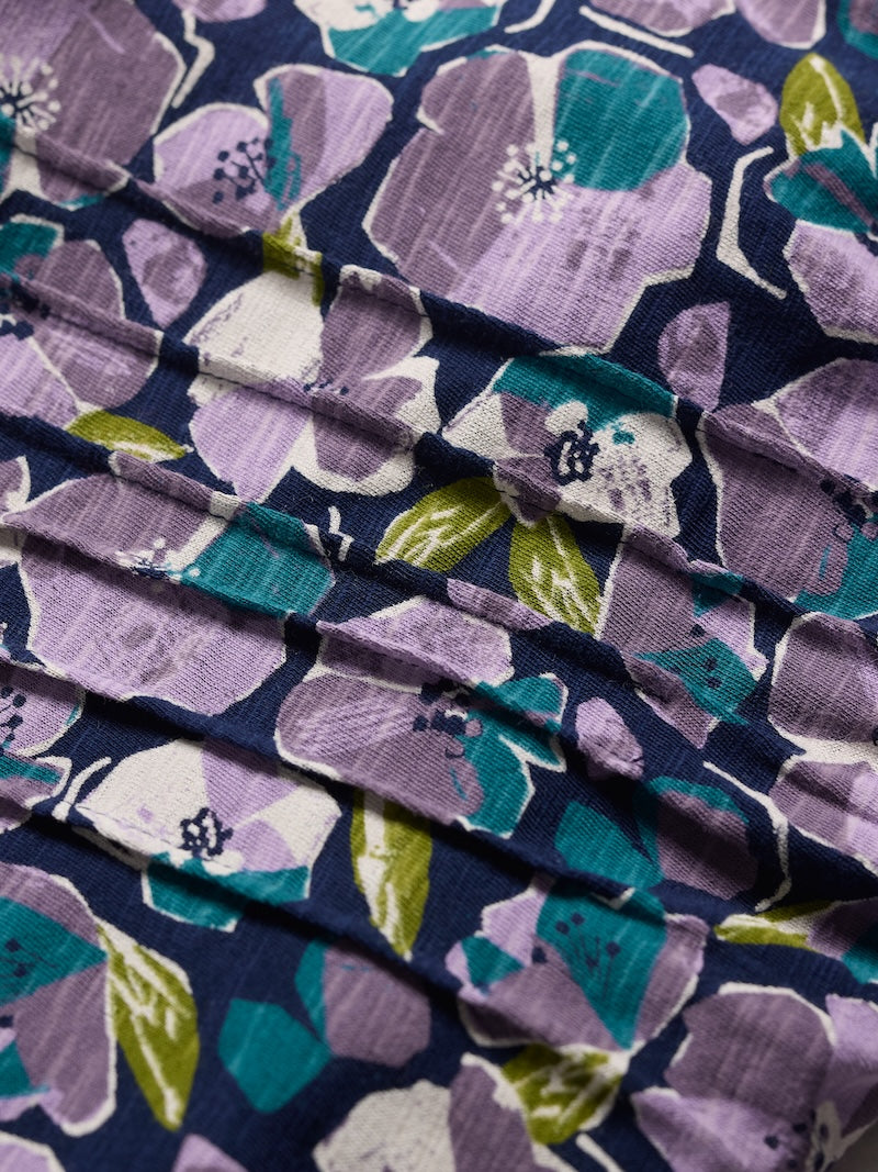 Close-up of floral fabric with purple, green, and white flowers on a dark blue background.