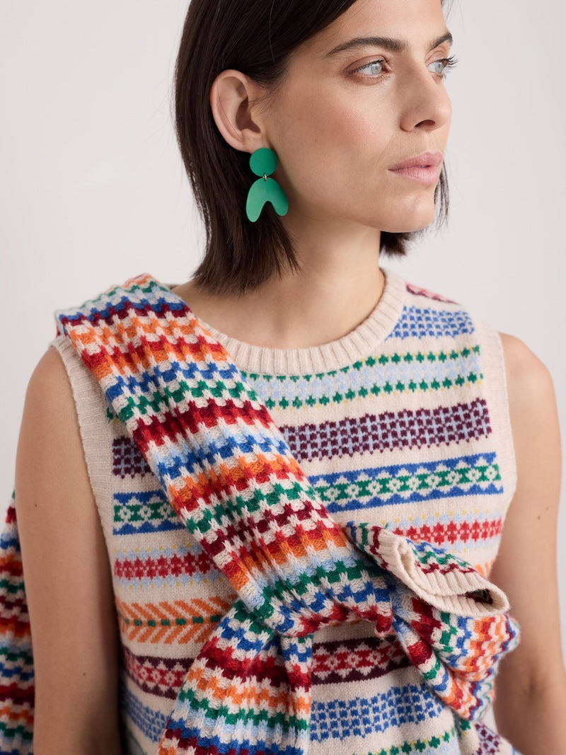 Woman wearing a colorful patterned sleeveless top with a plain background