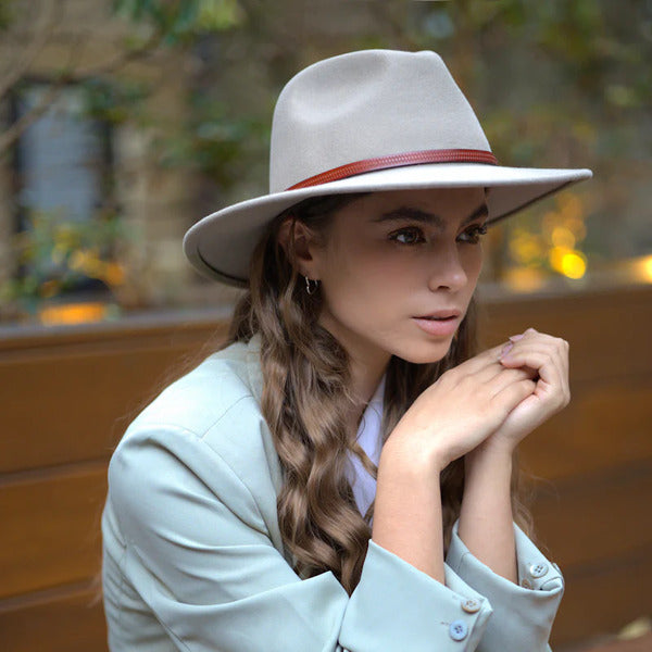 Light grey wool felt hat with brown band on female model outside