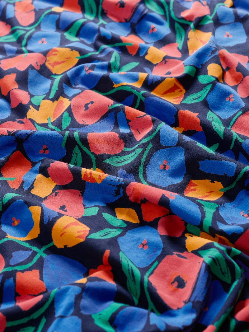 Close-up of colourful floral fabric with blue, red, yellow, and green patterns on a dark background.