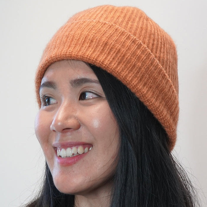 Woman wearing apricot orange possum, merino wool and silk beanie