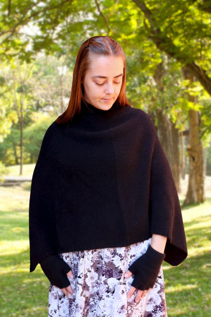 Woman wearing black possum & merino wool poncho in park. Warm, soft, lightweight lothlorian poncho