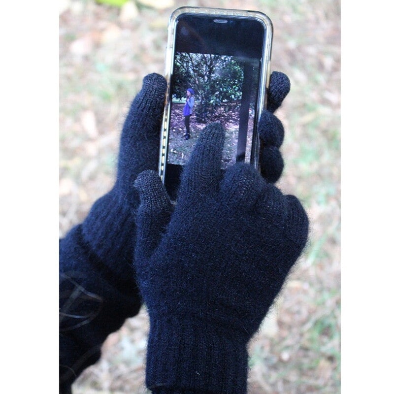 Lothlorian conductive black possum merino gloves being used to scroll on phone screen. Touchscreen compatible warm winter wool gloves