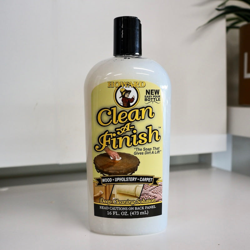 Howard's clean-a-finish wood, upholstery & carpet cleaner in bottle sitting on white bench. Safely cleans wood surfaces. Breaks down dirt & grease on wood surfaces. No harsh detergents, no solvents.