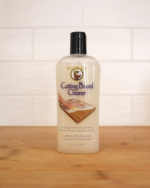 Howard cutting board cleaner bottle sitting on wooden chopping board on kitchen bench. Cleans & neutralises odours on well-used wood cutting surfaces, butcher blocks, wooden bowls and utensils. Food safe