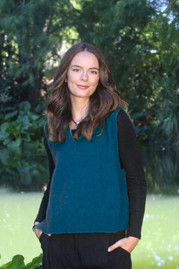 Woman standing in garden wearing blue warm winter possum and merino wool v-neck vest