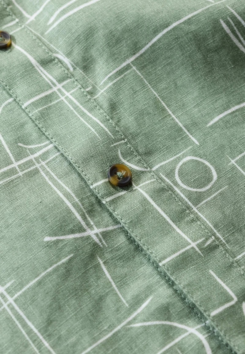 Close-up of a green fabric with white geometric patterns and buttons.