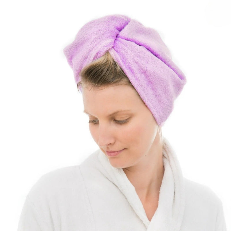Woman wearing white bath robe with purple bamboo hair towel.