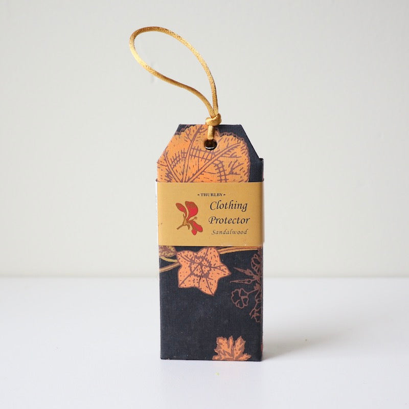 Sandalwood scented clothing protector moth repellent sitting on table with string on top for hanging in wardrobe