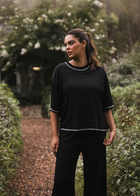 Woman wearing a black bamboo shirt and pants standing in a garden