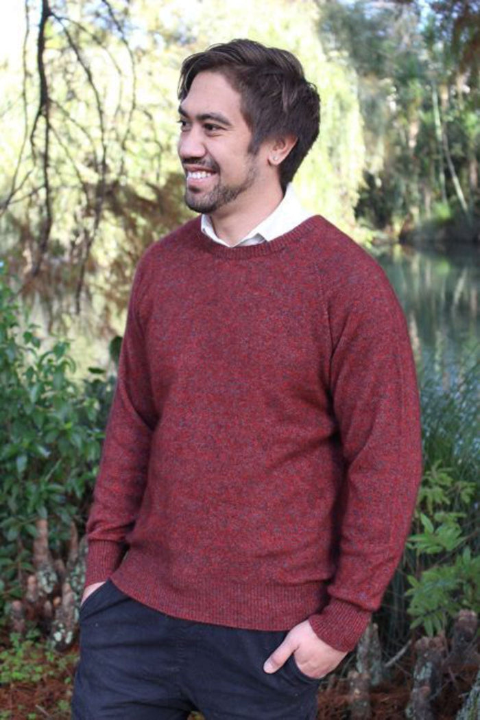 Rust coloured men's possum merino crew neck jumper on male model standing in a garden. Super warm, comfortable and soft Lothlorian crew neck jumper for men. Soft possum fur & warm merino wool.