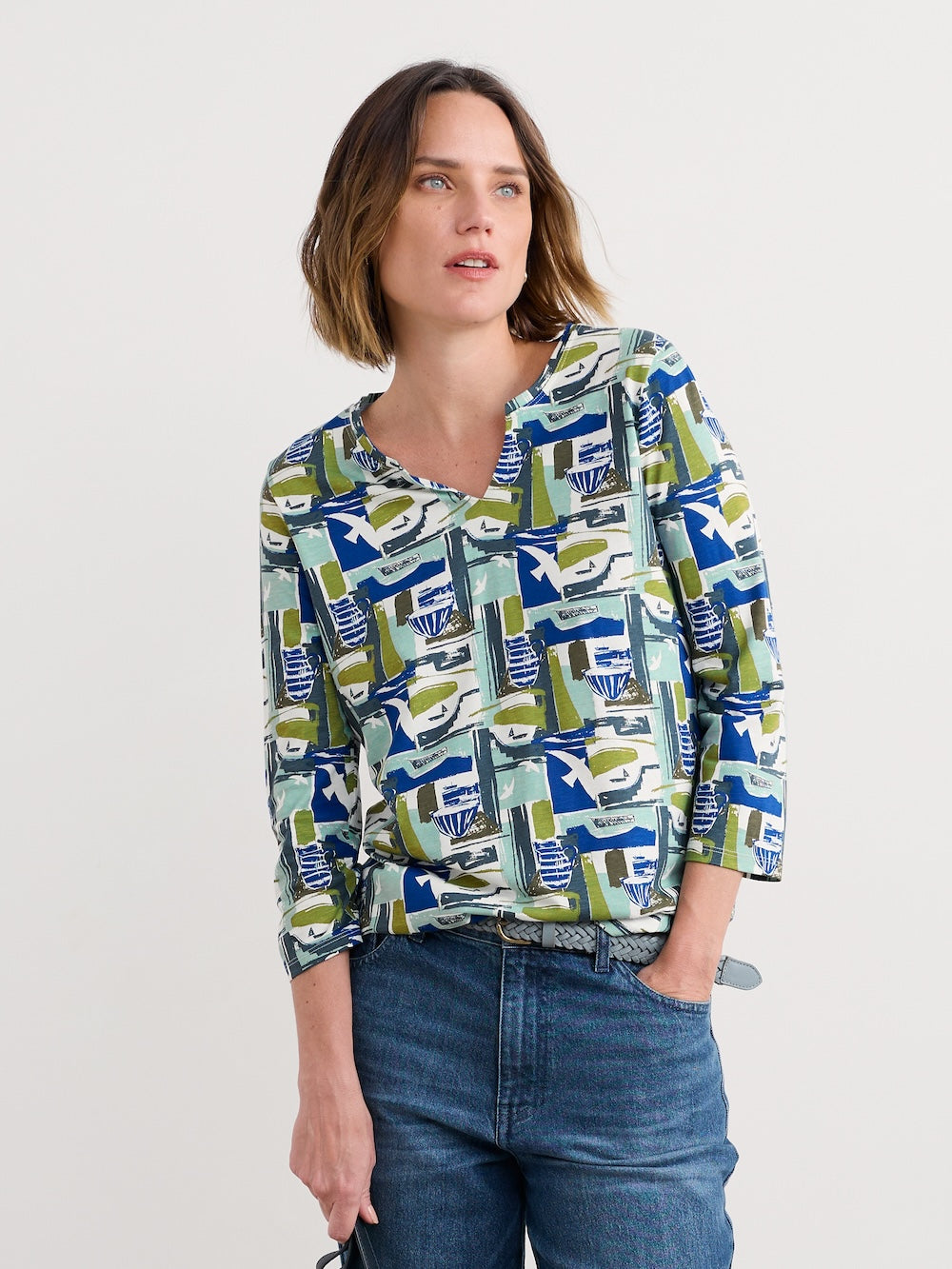Woman wearing a patterned blouse and jeans on a plain background