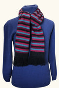 Purple, blue and black coloured striped possum and merino wool scarf wrapped around neck of mannequin wearing blue wool jumper on white background. Lothlorian warm, soft unisex winter scarf