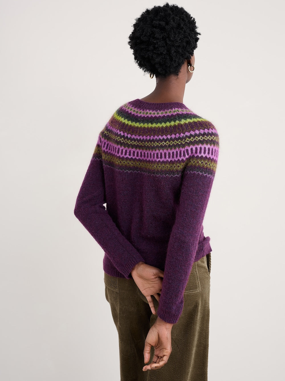 Person wearing a purple sweater with a patterned yoke against a white background