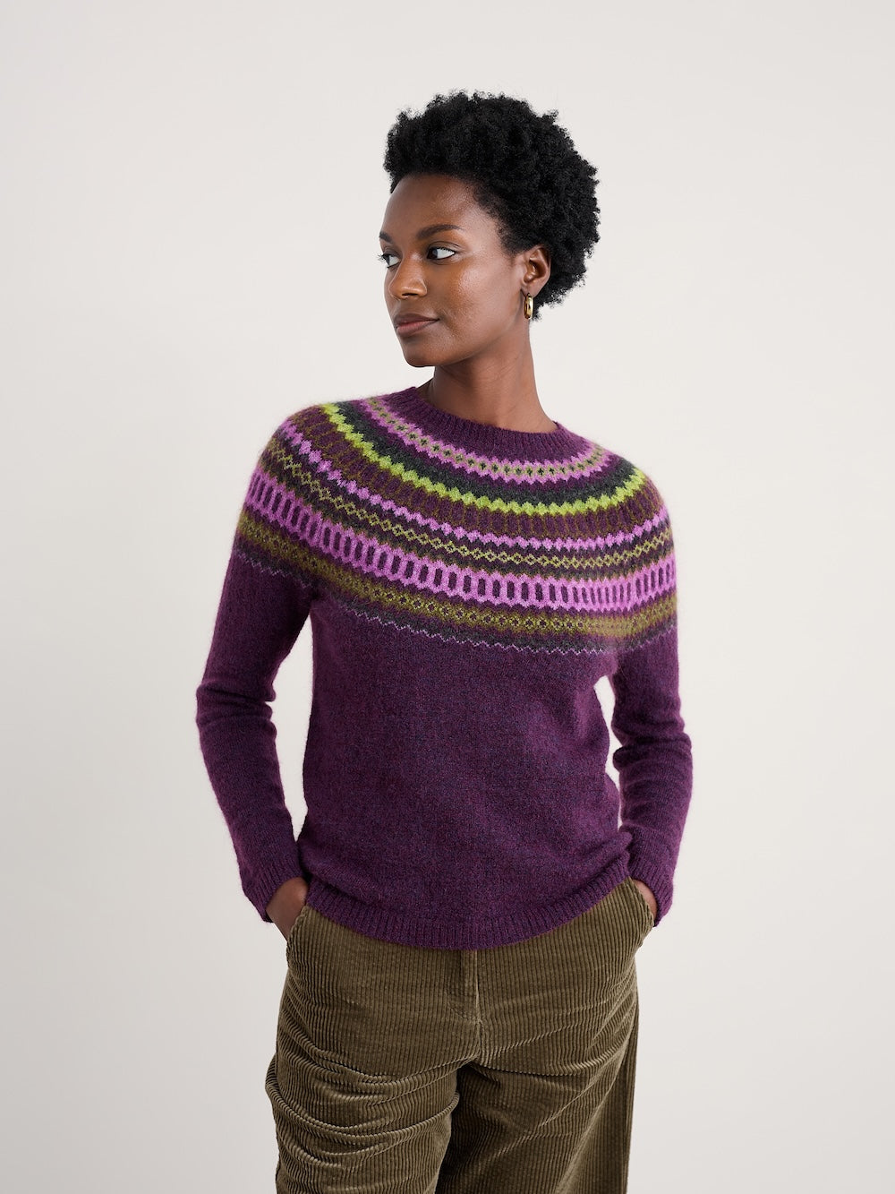 Woman wearing a purple sweater with a colorful pattern on a plain background