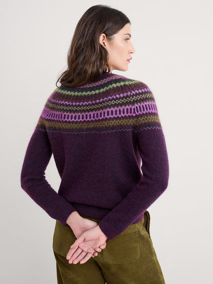 Woman wearing a purple sweater with a patterned yoke against a plain background