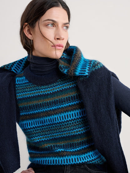 Woman wearing a blue and black striped vest with a plain background