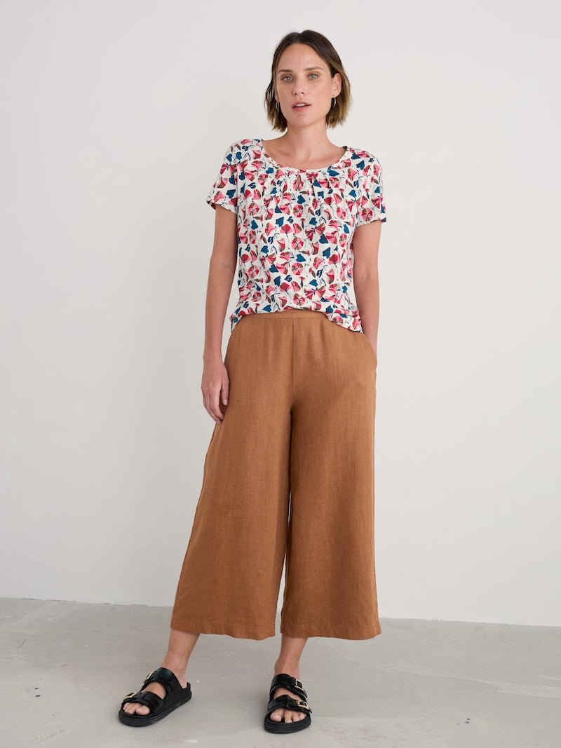 Woman wearing a floral top and brown pants on a white background