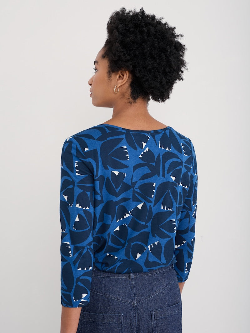 Woman wearing a blue floral patterned top against a plain background