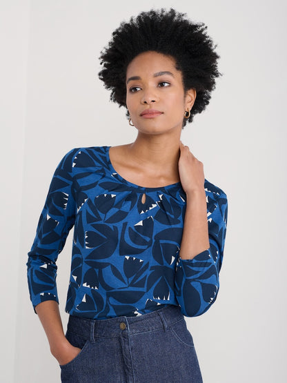 Woman wearing a blue patterned top against a plain background