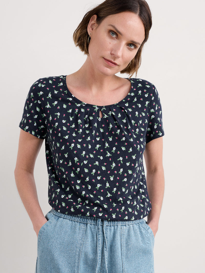 Woman wearing a navy blue floral blouse against a white background