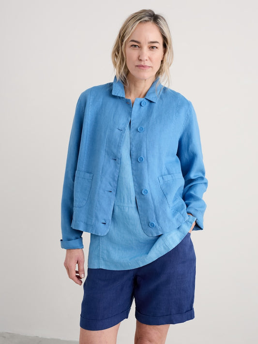Woman wearing a blue shirt and shorts against a plain background