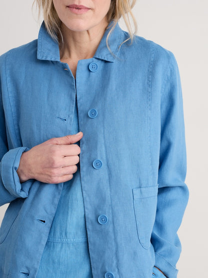 Person wearing a blue linen jacket on a plain background