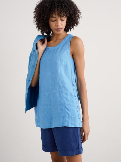 Woman wearing a blue sleeveless top and shorts on a plain background