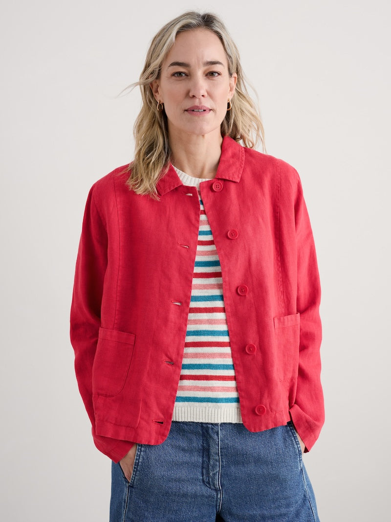 Woman wearing a pink jacket over a striped shirt with a plain background