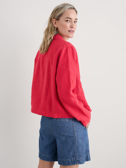 Person wearing a pink jacket and blue shorts on a plain background