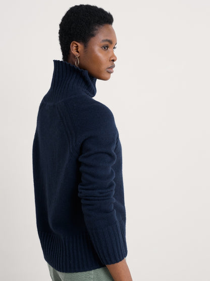 Person wearing a navy blue turtleneck sweater on a light background