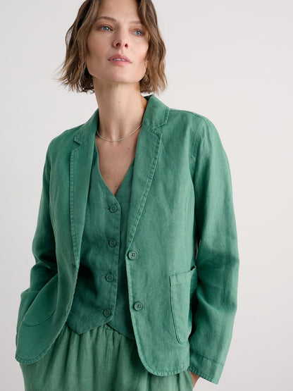 Woman wearing a green blazer over a matching top against a plain background