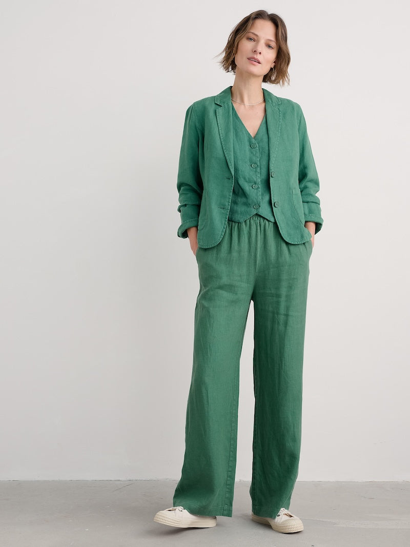Woman wearing a green jacket and pants standing against a white background