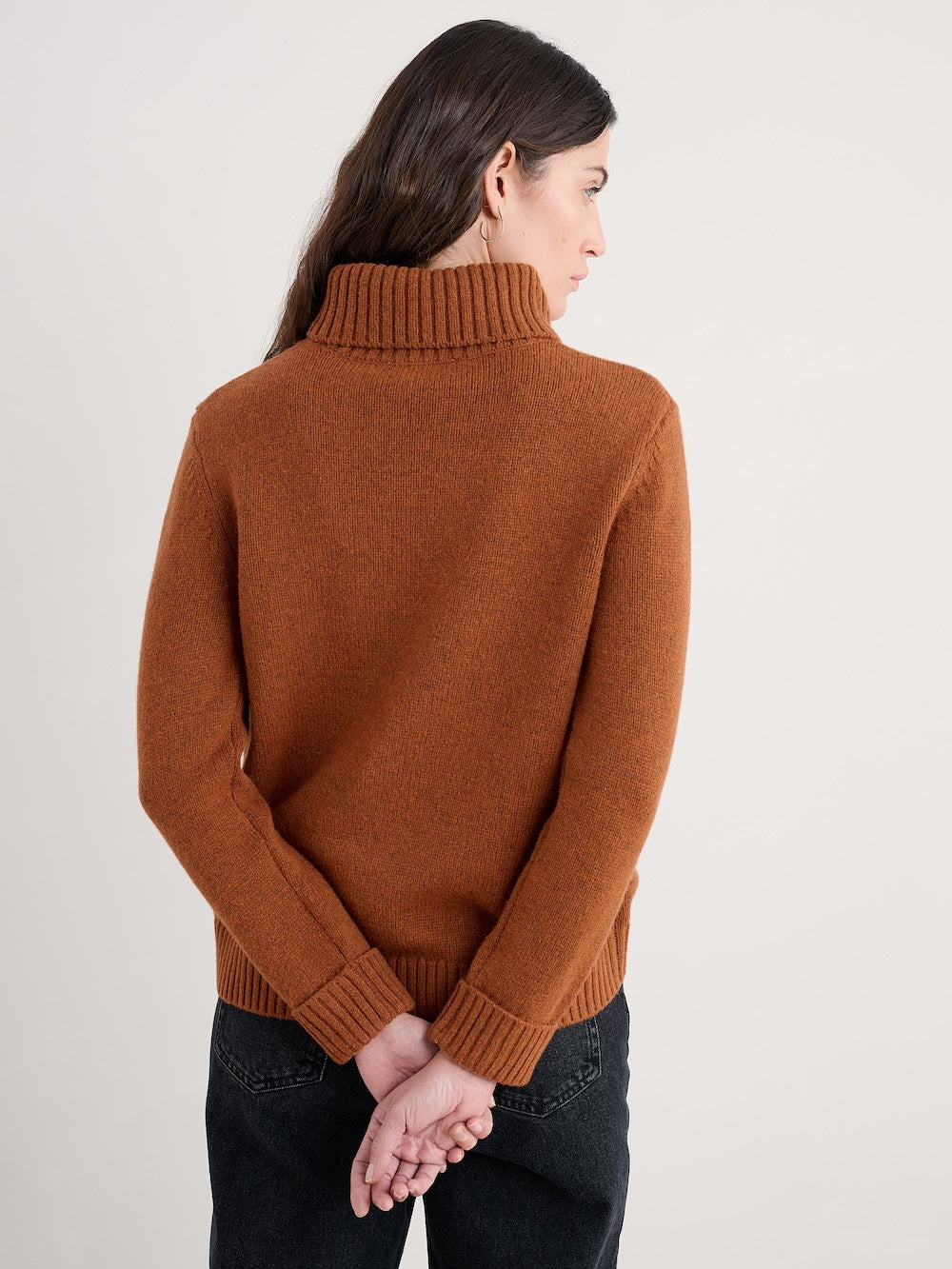 Person wearing a brown sweater against a plain background