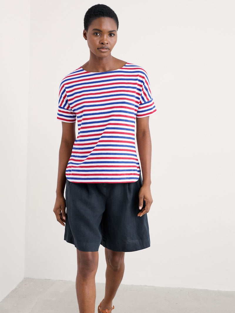 Woman wearing a red, white, and blue striped shirt with black shorts on a white background