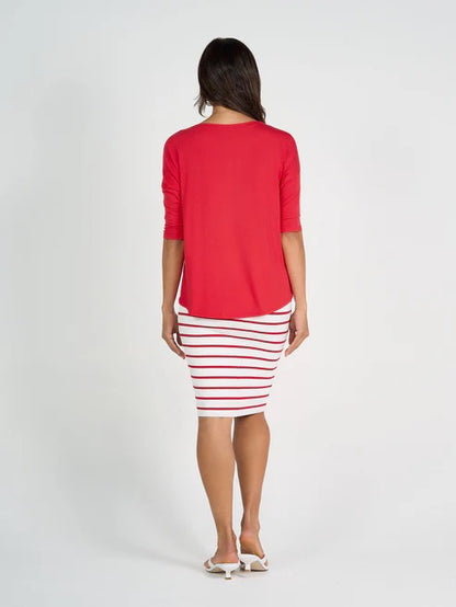 Woman wearing a red bamboo 3/4 length sleeve top and striped skirt on a white background