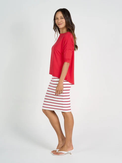 Woman wearing a red bamboo 3/4 length sleeve top and striped skirt on a white background