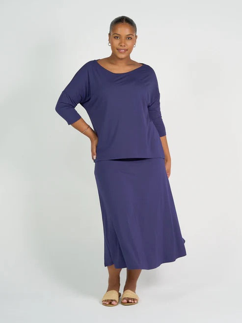 Woman wearing a blue bamboo 3/4 length sleeve top and navy skirt on a white background
