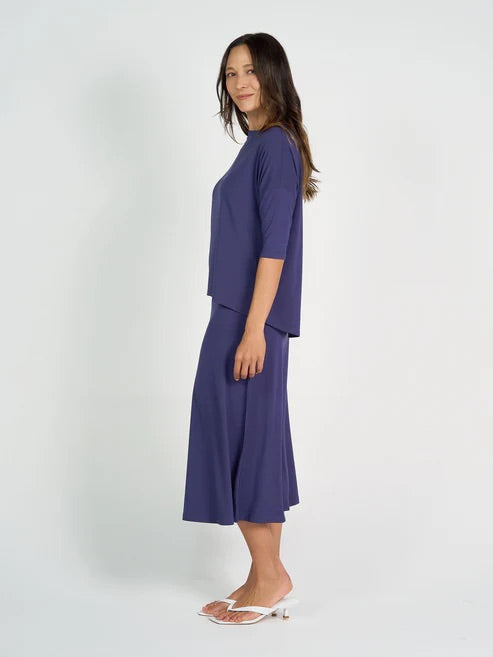 Woman wearing a blue bamboo 3/4 length sleeve top and navy skirt on a white background