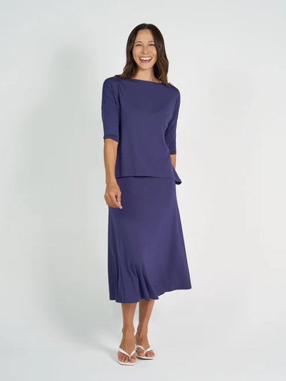 Woman wearing a blue bamboo 3/4 length sleeve top and navy skirt on a white background