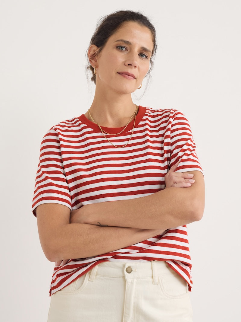 Woman wearing a red and white striped shirt with arms crossed on a plain background