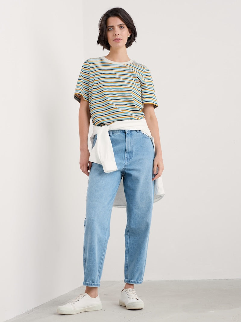 Woman wearing a striped shirt and blue jeans against a white background